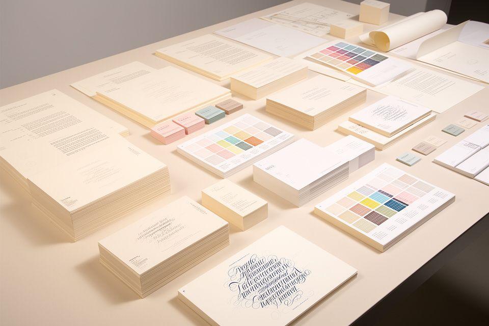 Estudio de papelería con pliegos, pruebas de color y caligrafía fina sobre una mesa amplia