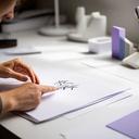 Directora de estudio de diseño revisando pruebas de caligrafía en una mesa de trabajo luminosa
